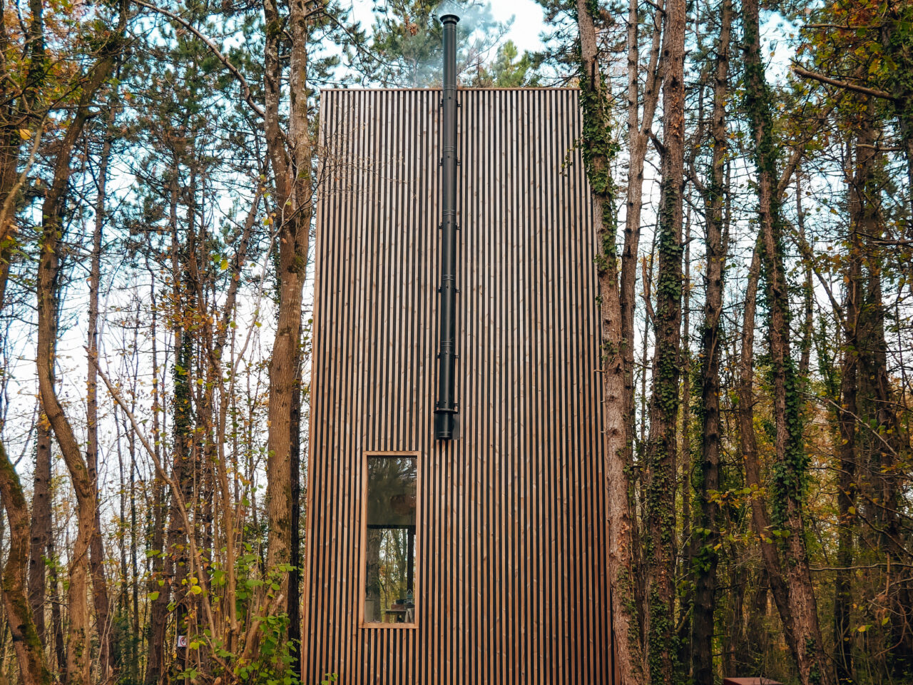 tuinkantoor in een bos met een raam en schouw